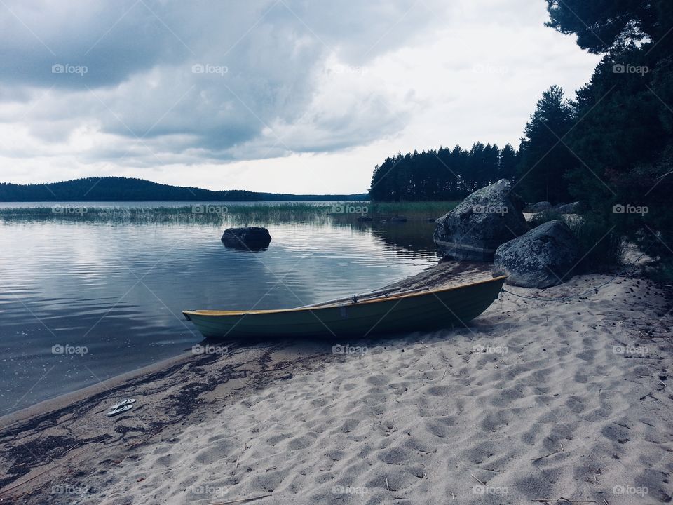 A sandy beach with a wooden Rowing boat in an island of a Finnish lake