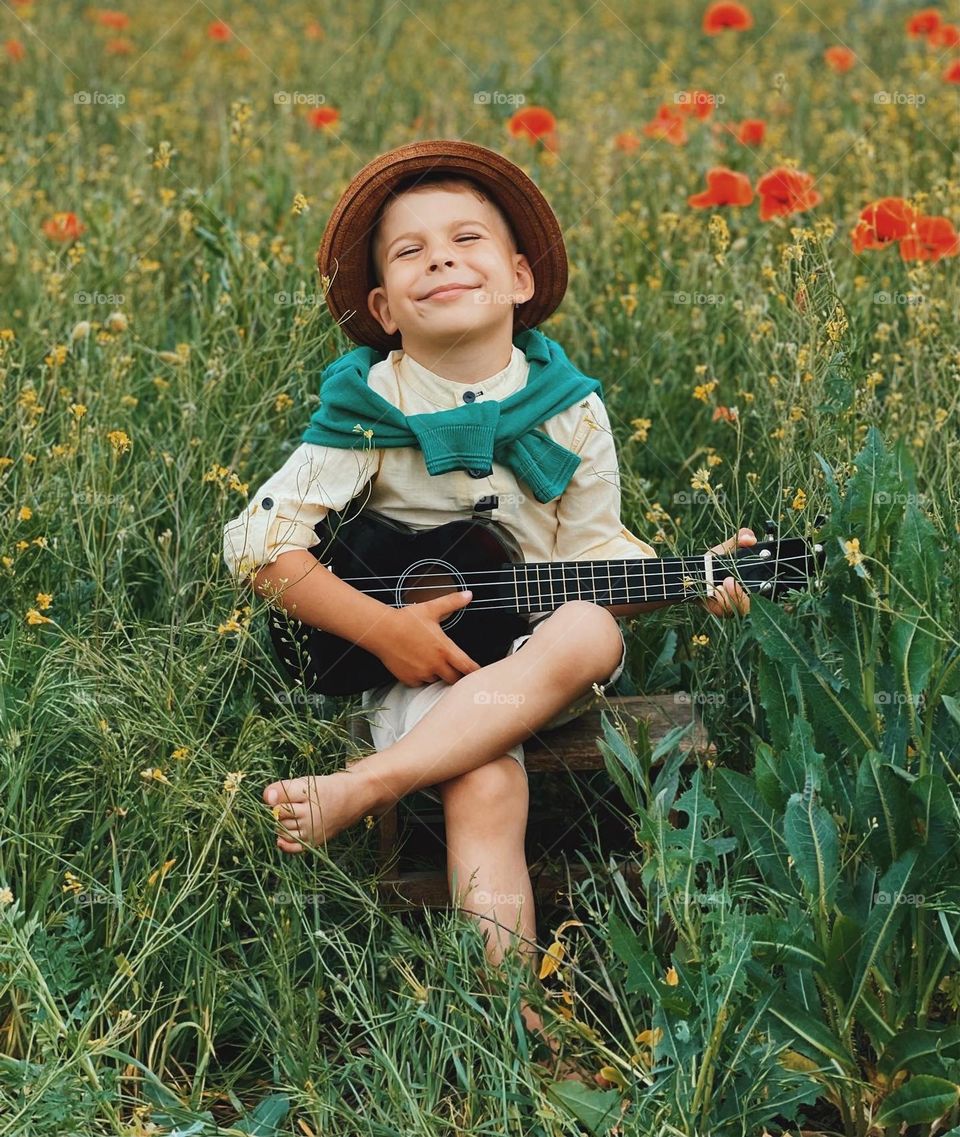 Smiling BOY playing on a guitar 