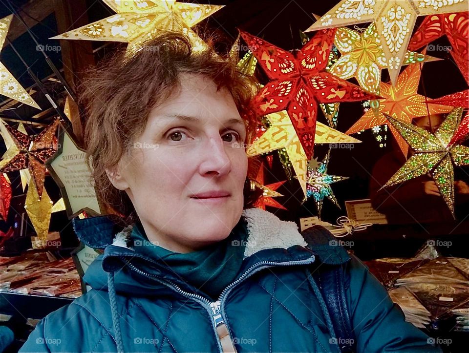 In midst of the festive stars of Christmas displayed on the “Odeonsplatz” in “München”, capital of “Bavaria”, Germany this lovely lady looks even prettier and also happier as she shows us with her smile. 2023. Hypnotic Productions