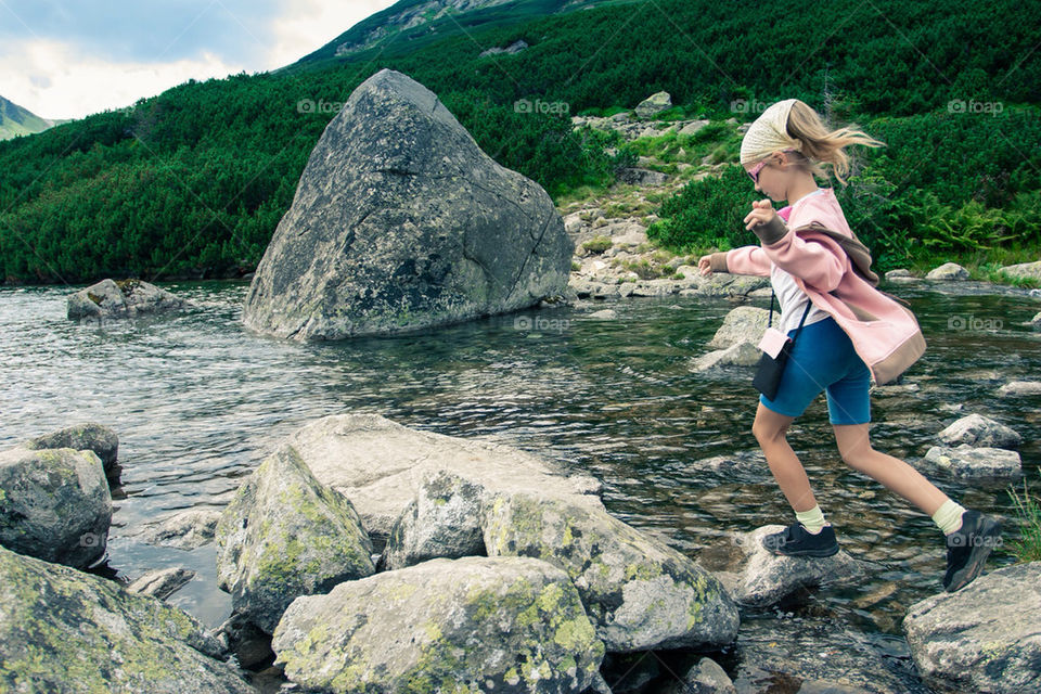 Little girl jumping from stone to stone