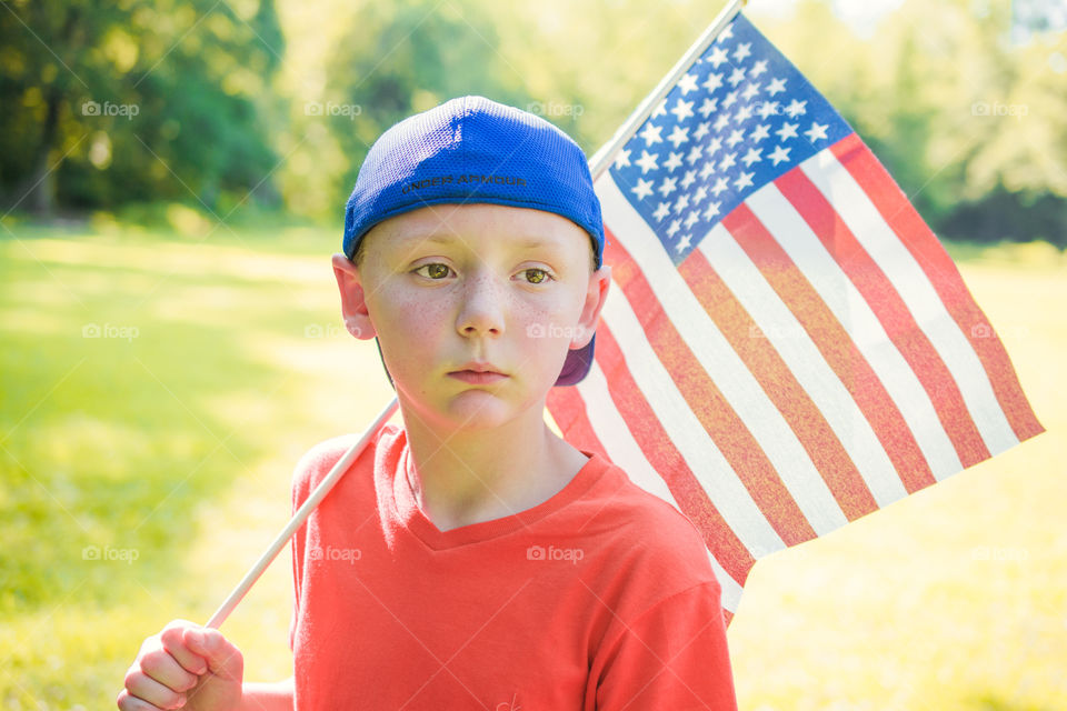 Young Boy in Blue Cap Carrying American Flag