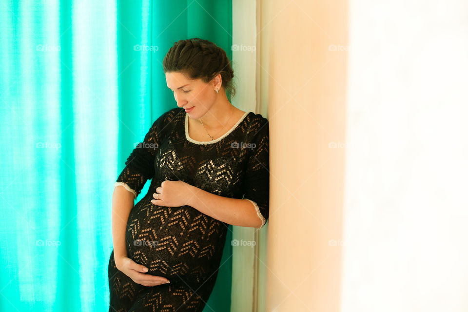 Close-up of a pregnant woman leaning on wall