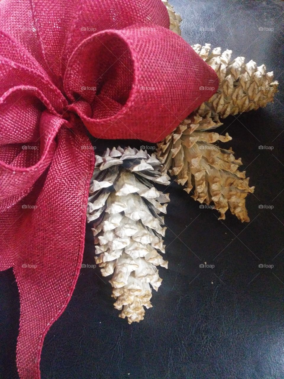 Giant red fabric mesh bow with bleached white pine cones closeup homemade holiday festivite decorative