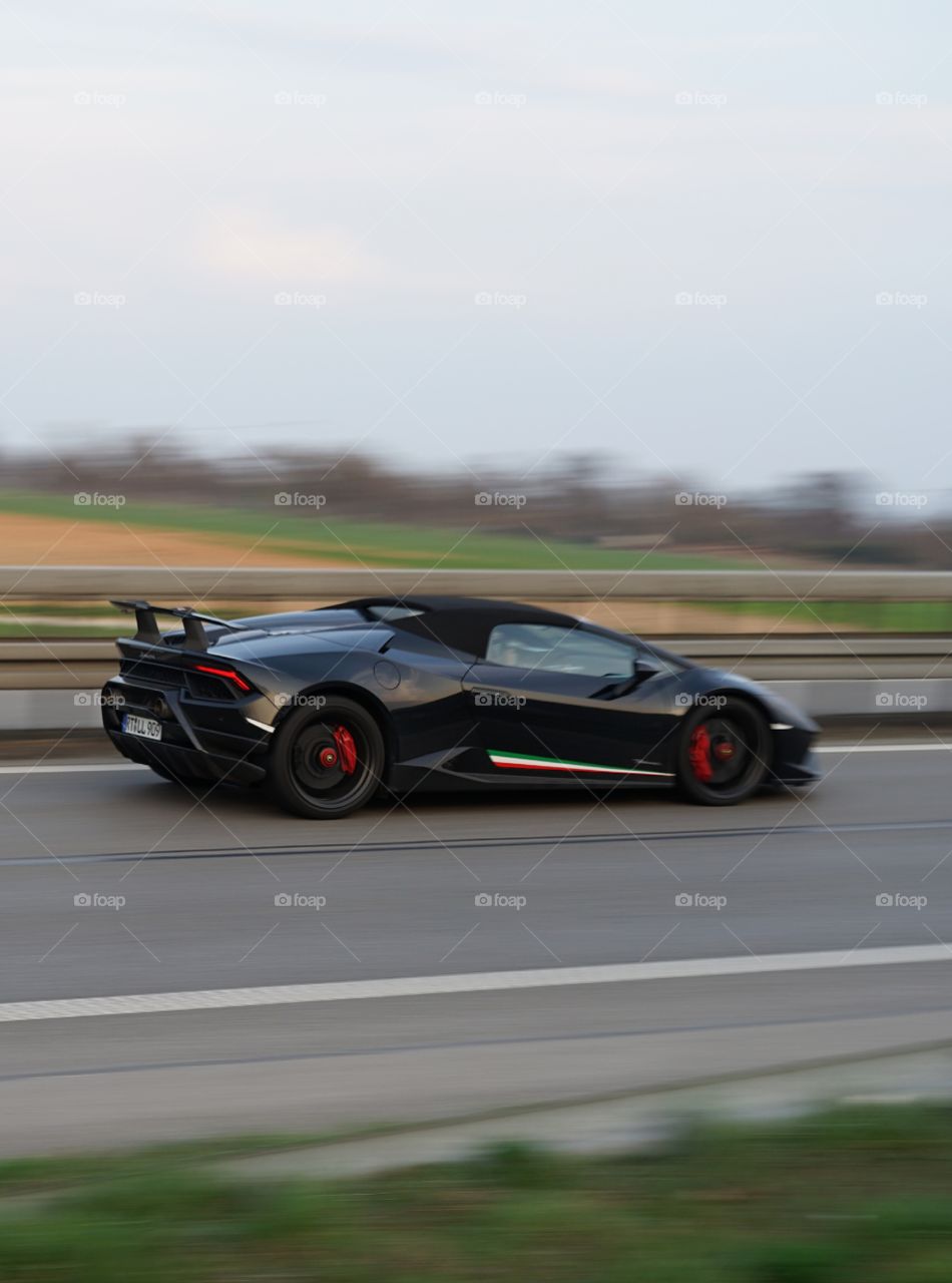 very rare sports car driving fast on german motorway . fly by pic
