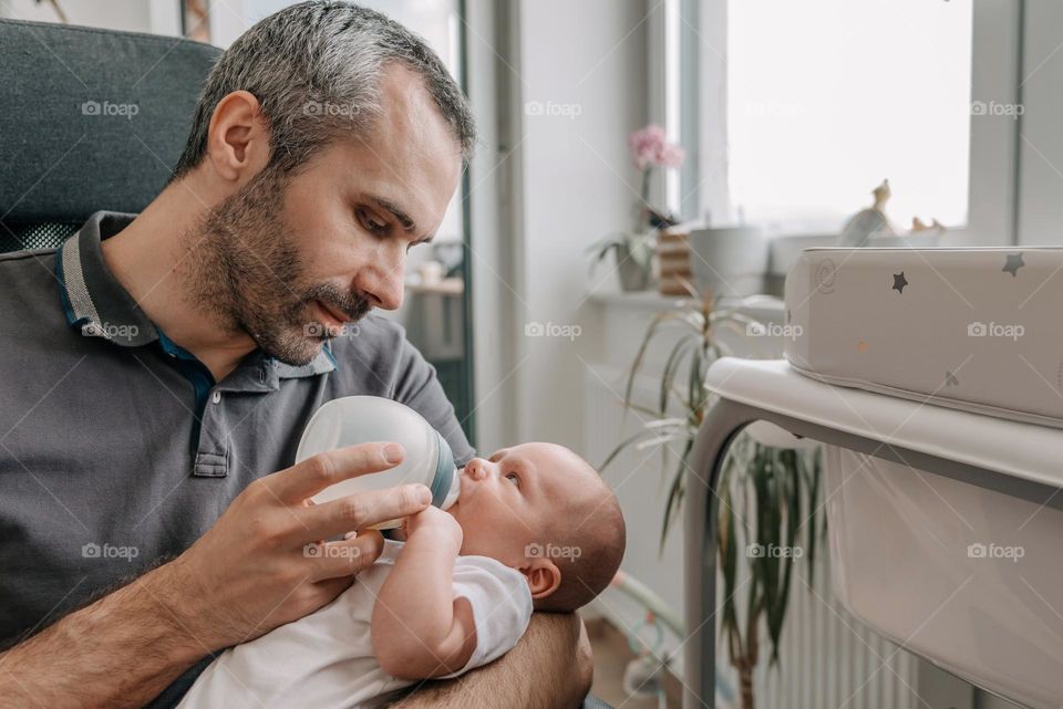Father feeding baby son with bottle of baby formula