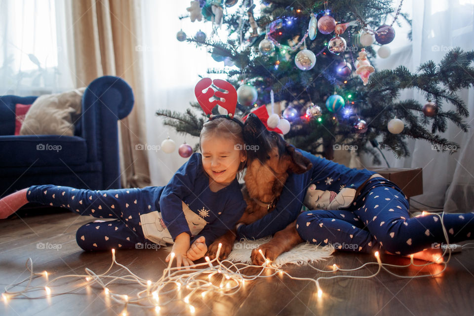 Little sisters with German shepherd puppy near Christmas tree 