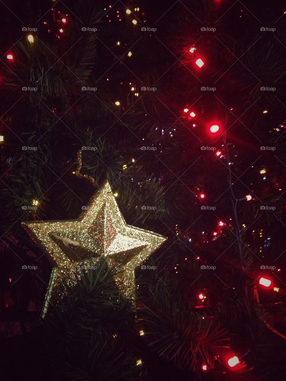 Gold plastic star, balls, red lights garland and other Christmas decorations on artificial fir tree in Moscow, Russia