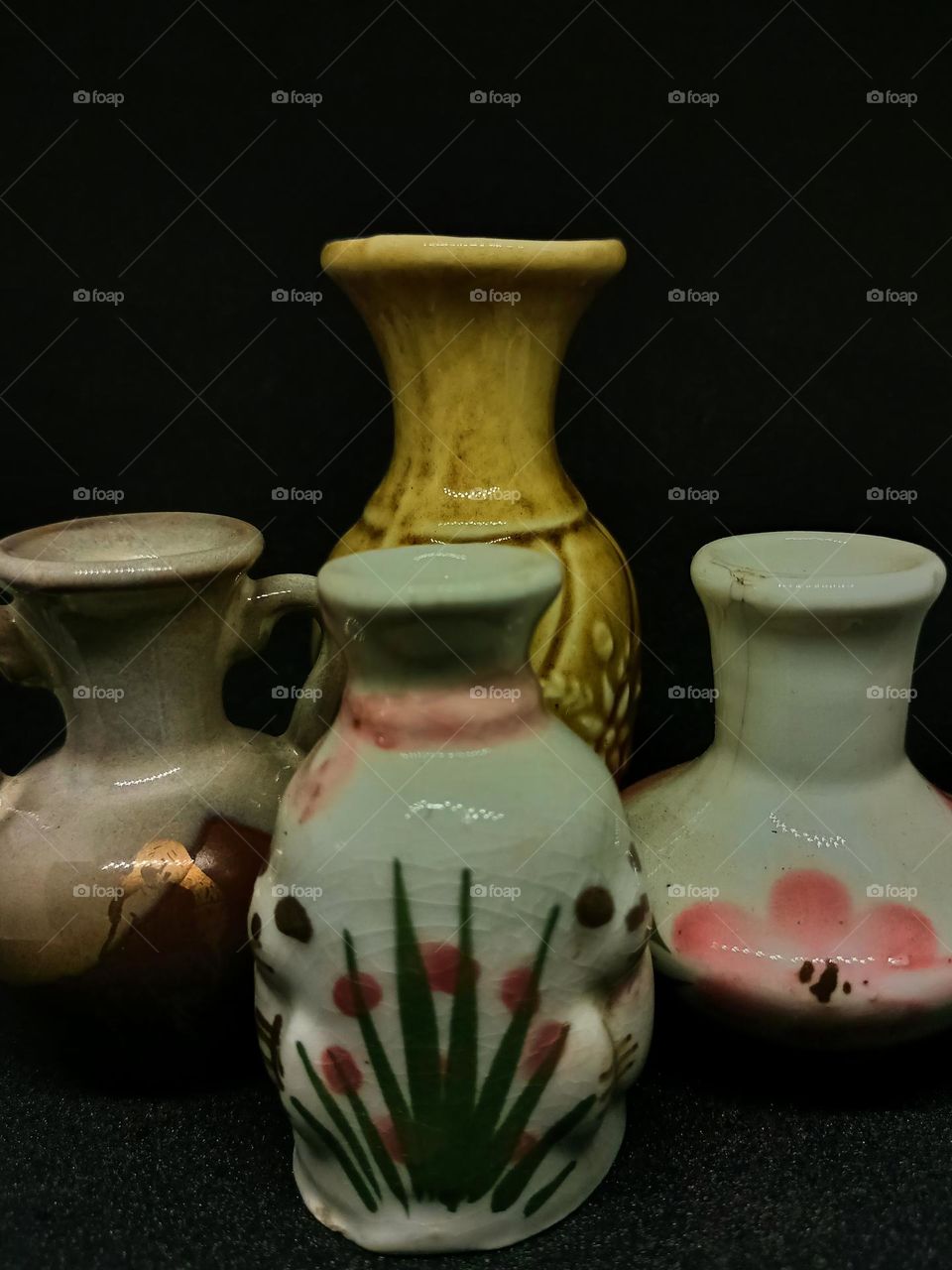Still life with Variations of earhenware Pot and bottles isolated on black background