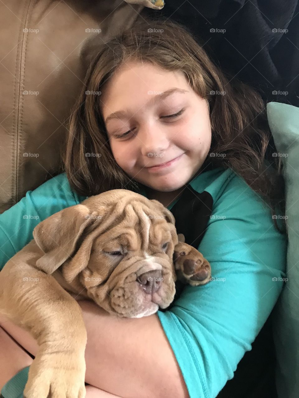 A little girl happily loving her new bulldog puppy. 