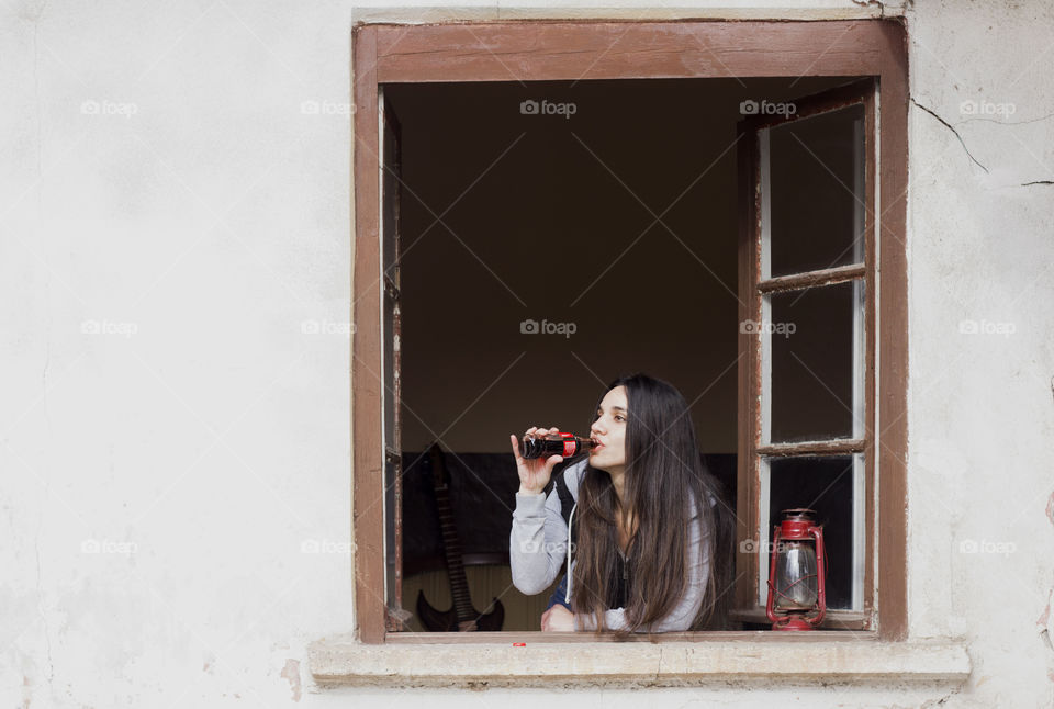 Beautiful woman drinking Coca-Cola on the window