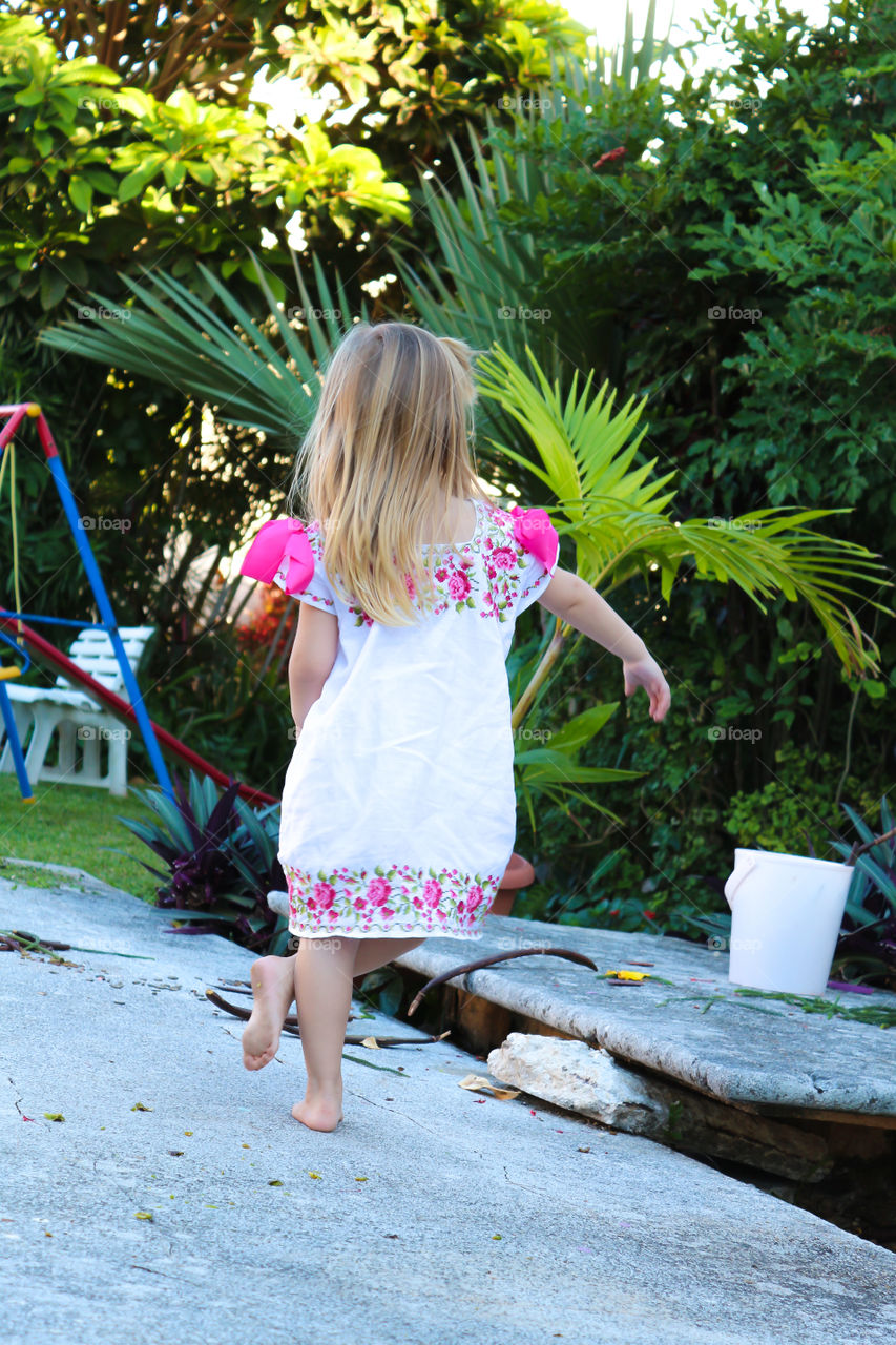 Little girl playing outside with the typical Yucatan Hipil dress 
