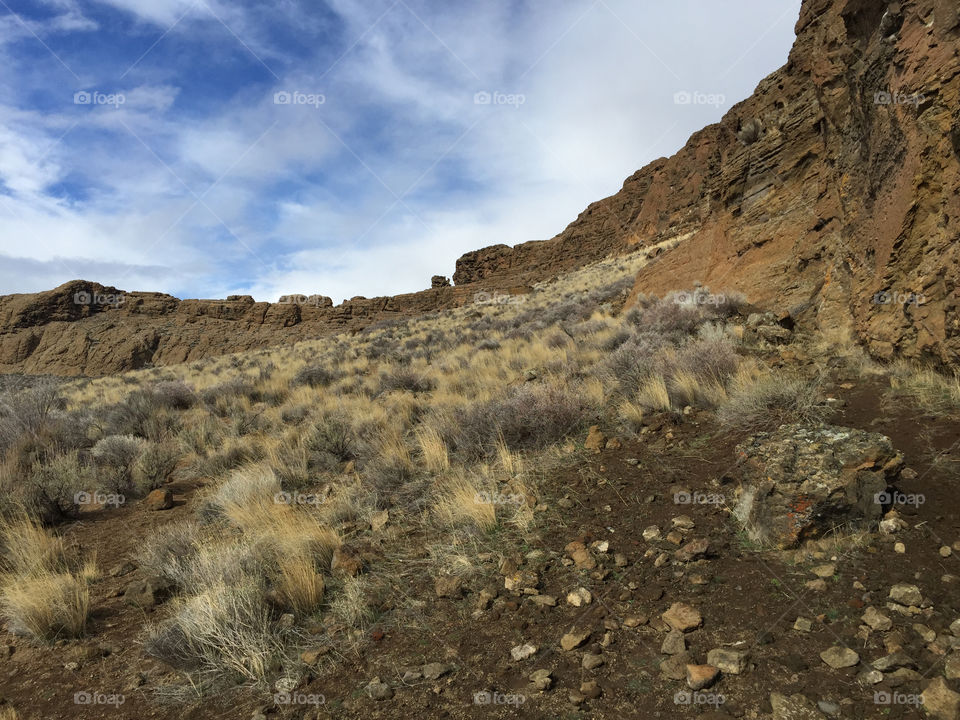 The inside ground of the magnificent Fort Rock with blue sky peaking through the clouds. 