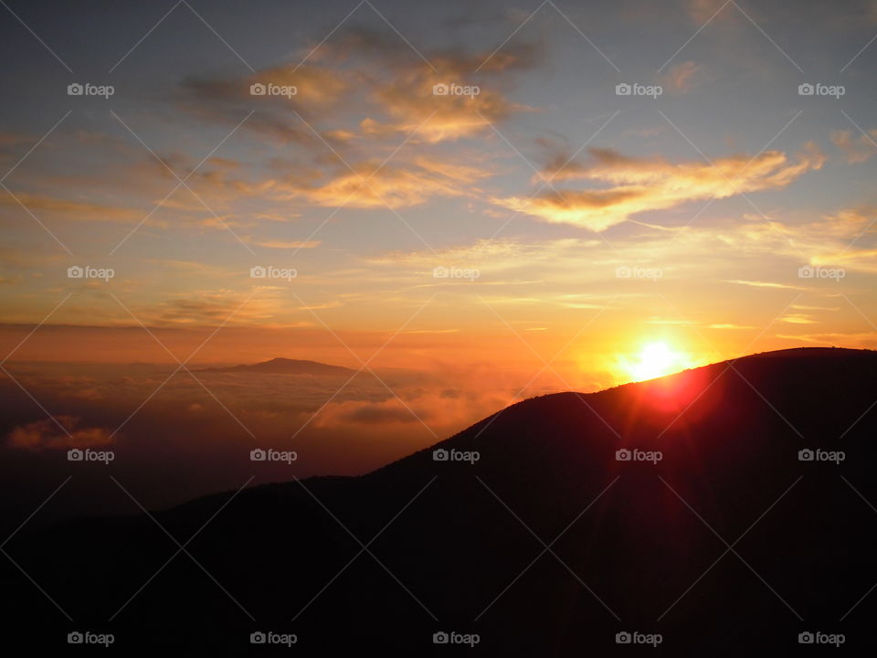 View of the sun setting into the clouds from Mauna Kea. 