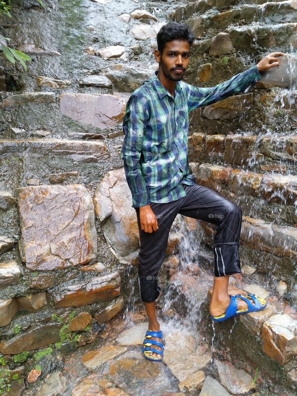 Indian young man standing near waterfall