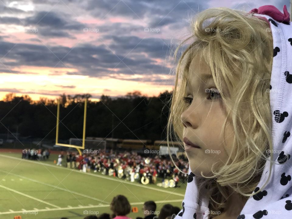 Cute kiddo being bored at a Friday night high school American football game 