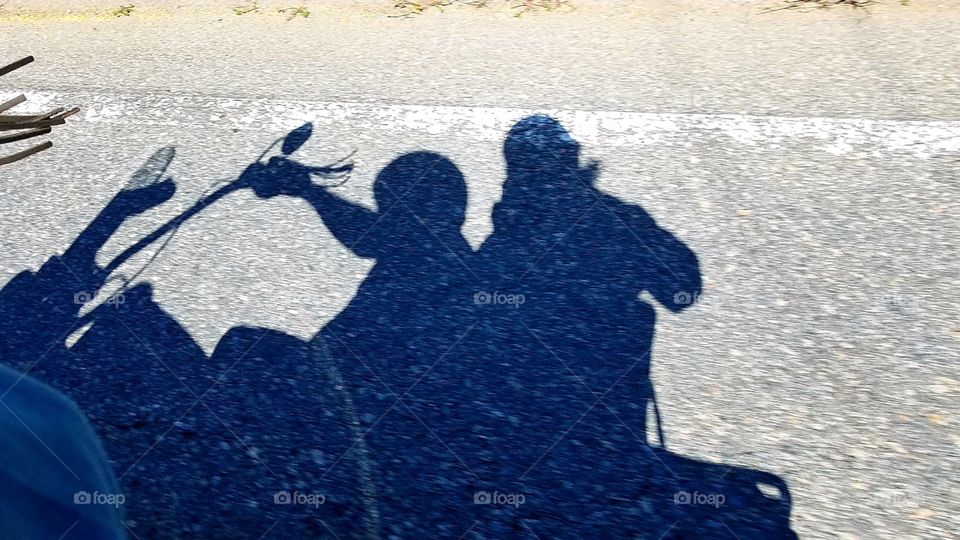 Shadow of two bikers on a motorcycle taking a daytime ride on a sunny highway, street or road.✌ Asphalt is old, dark gray, you can see breakdown lane marked with a solid white line.