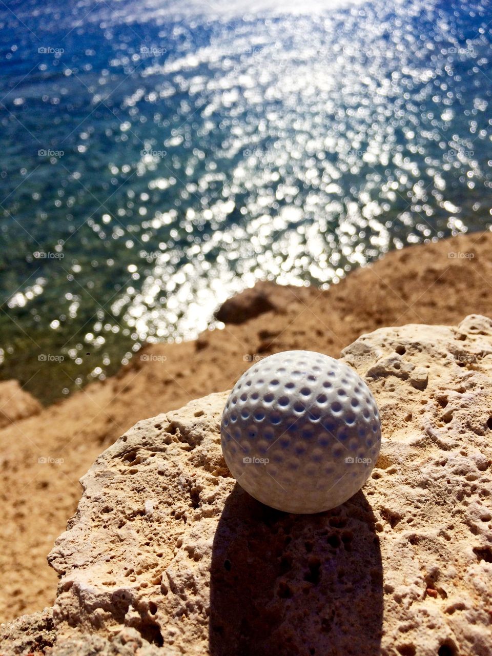 Golf ball on rock at sea