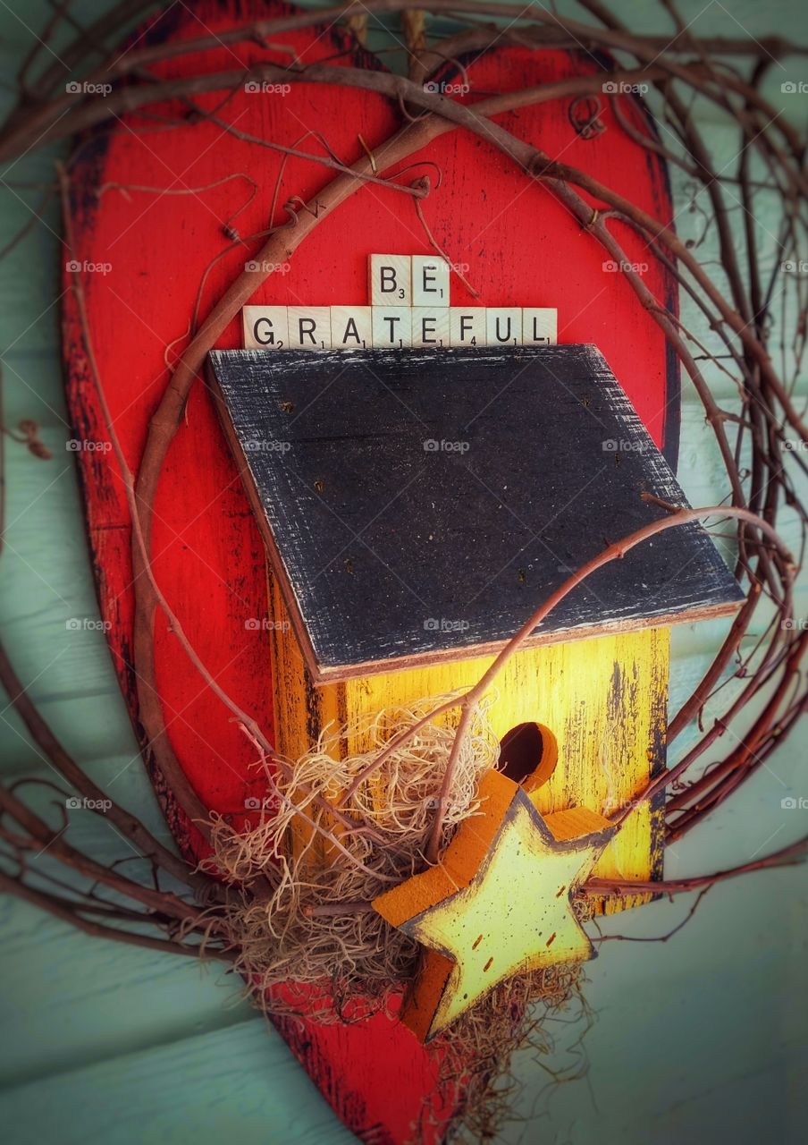 Be Grateful written on a big red wooden heart with birdhouse star, new year's resolutions