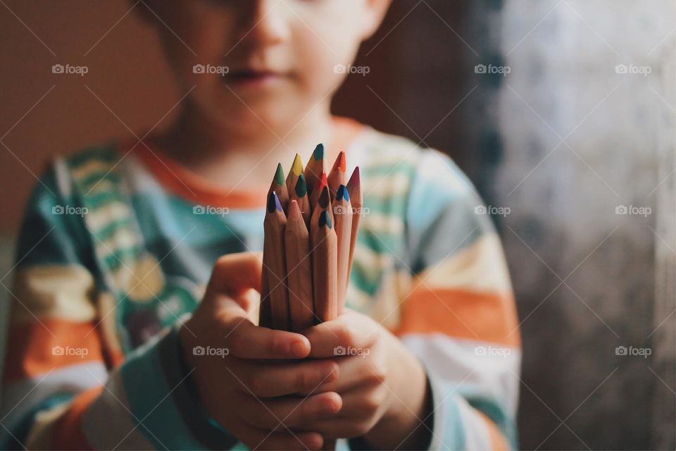 Kid holding a bunch of colorful pencils 