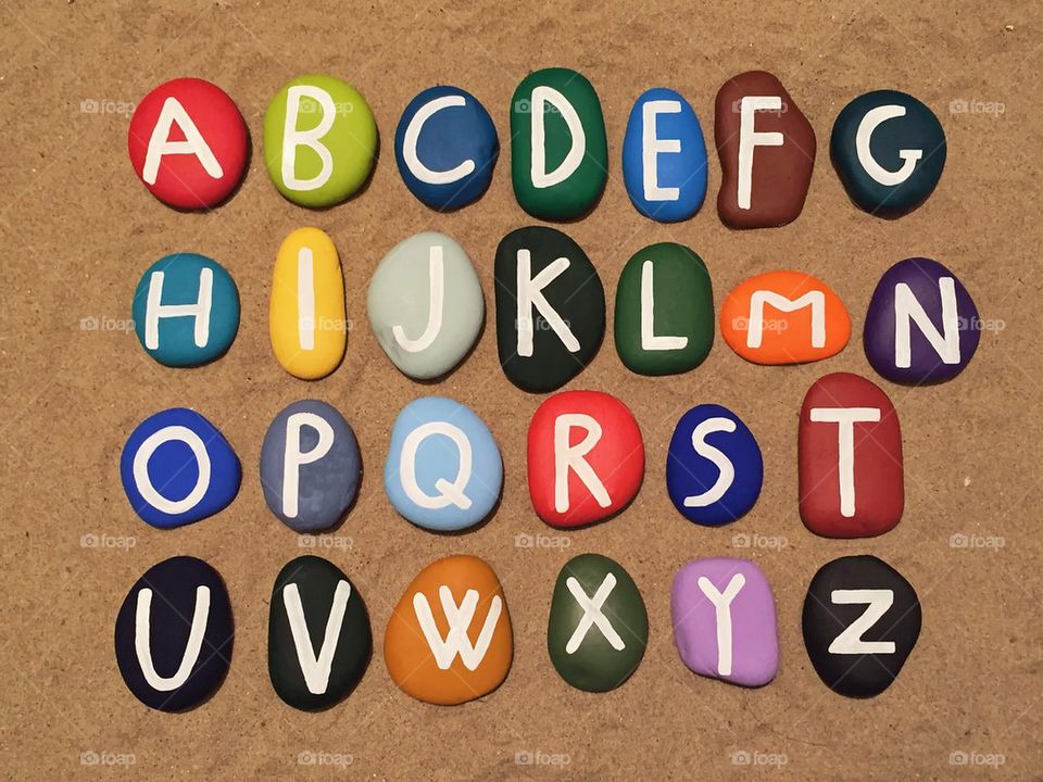 Colored stones alphabet on the sand