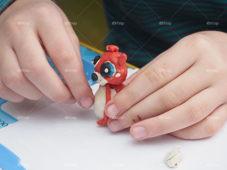 The child sculpts from plasticine a small figure of an animal.  Home creativity.