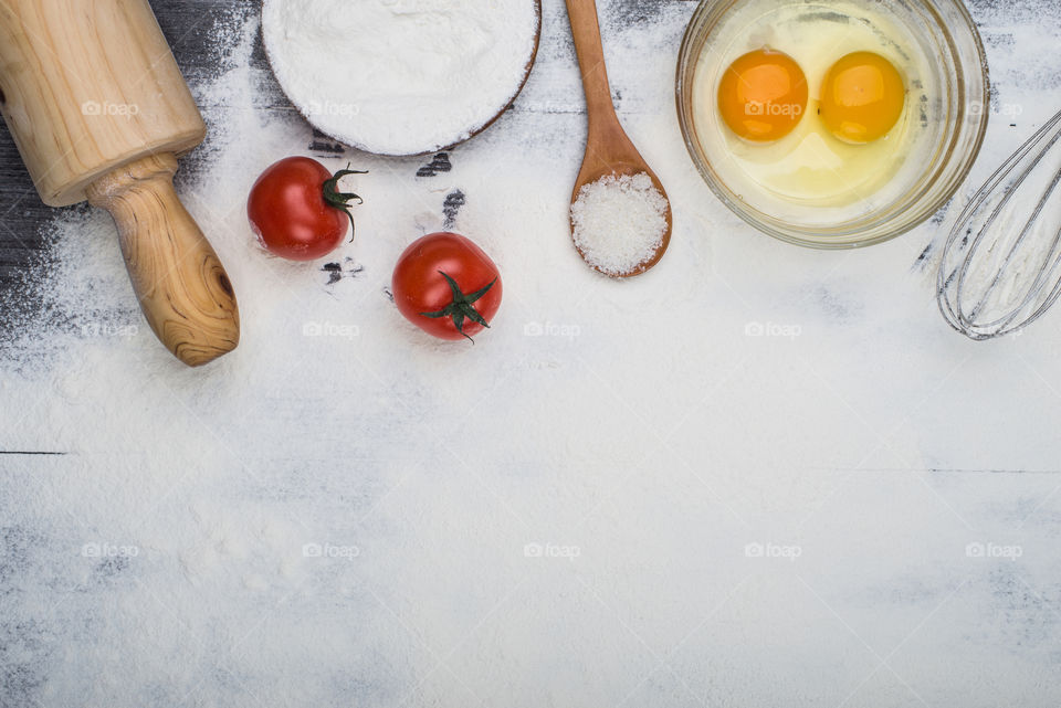 Top view of table full of flour, eggs and tomatoes