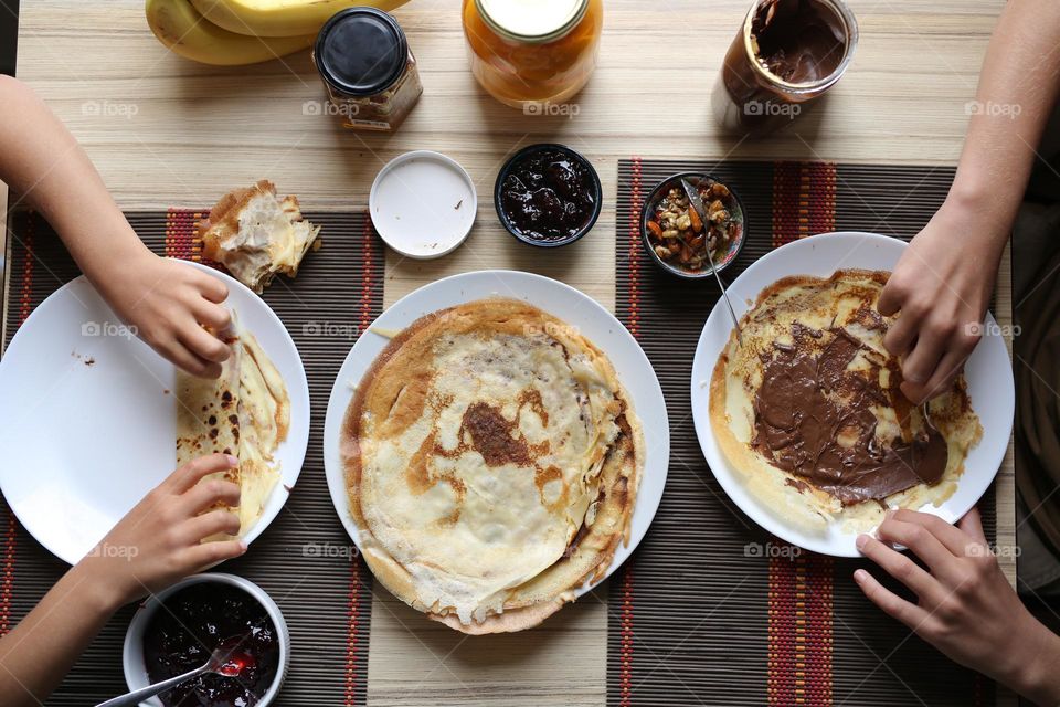 two brothers have breakfast, round plates on the table, round pancakes on the bottom, top view