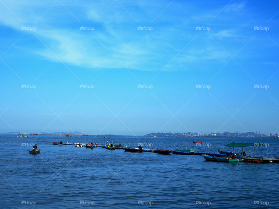 Fishing boats in line formation near a public pier ready for the day's work.