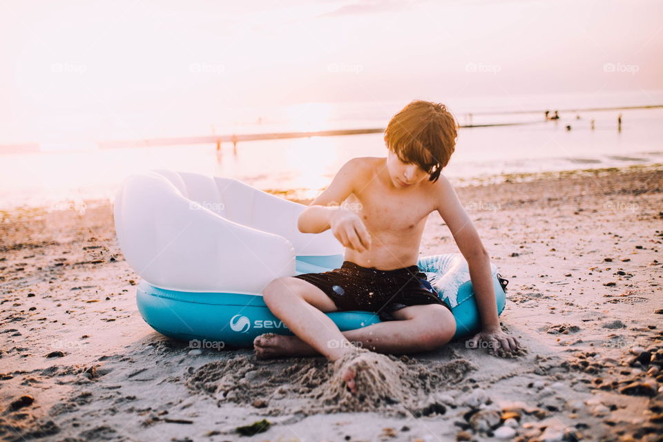 Young boy playing with sand on the beach 