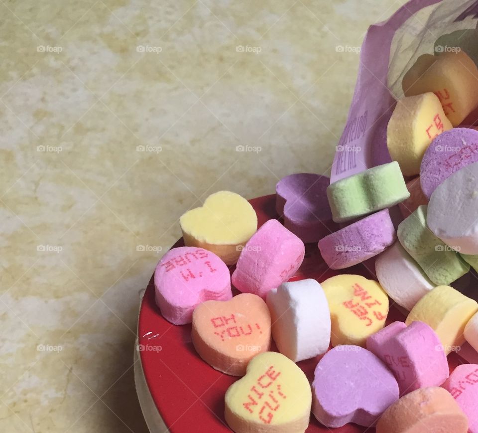 Multicolored traditional Valentine's Day candy sitting on the edge of a red heart