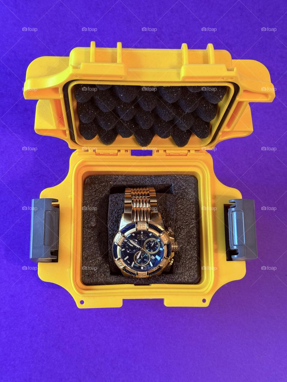 High contrast man’s watch in bright yellow case against solid purple background 