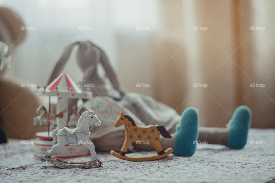 Children’s toys in room at daylight. Rocking horse, carousel, bunny, teddy bear