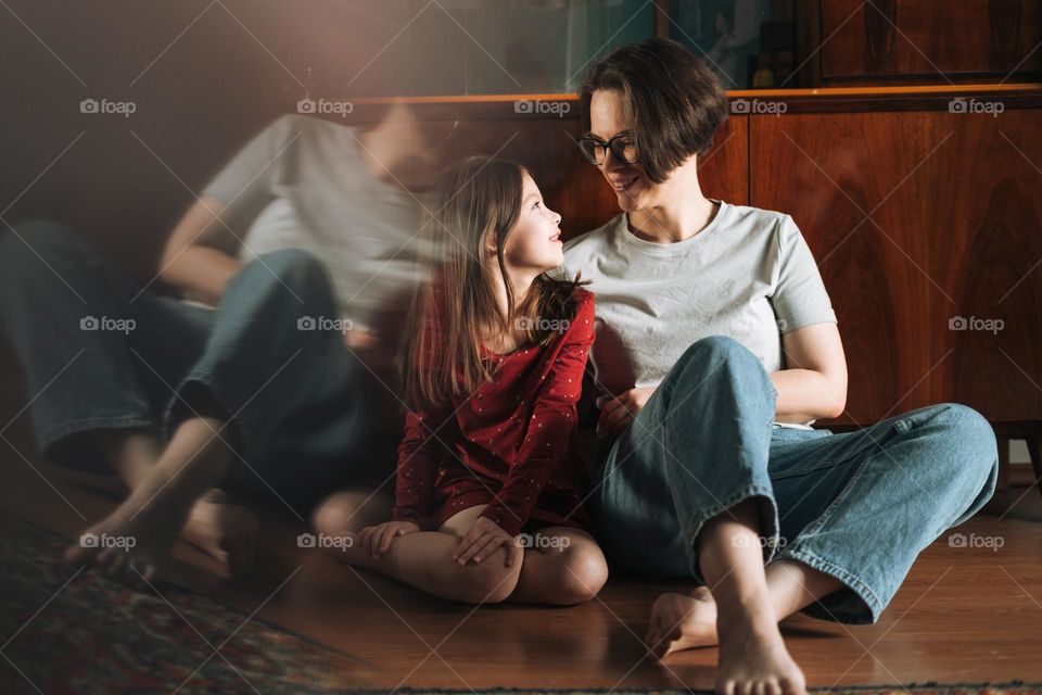 Tween girl and her mother sitting on the floor in living room at home