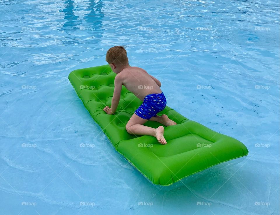 a boy on a green inflatable mattress