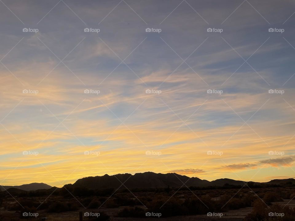 A colorful sunset with yellow clouds and beautiful mountains.