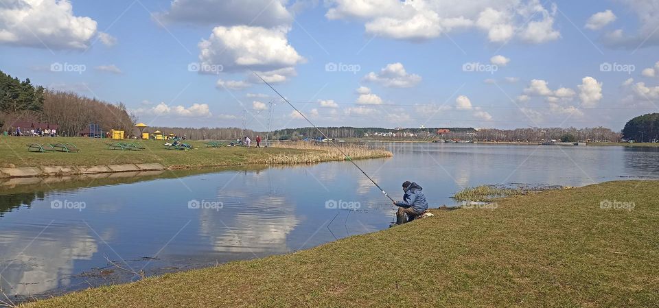 city lake shore and fisherman fishing