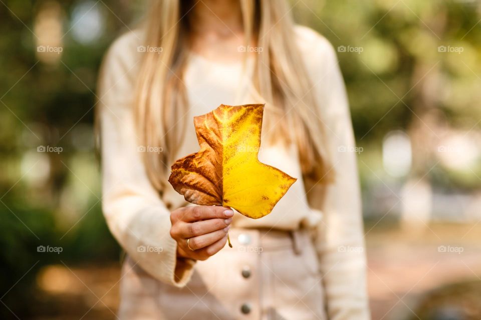 Woman holding hand fallen leaf at autumn