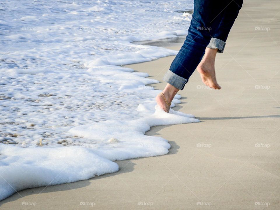 Low angle view of a woman avoiding the waves on a sandy beach