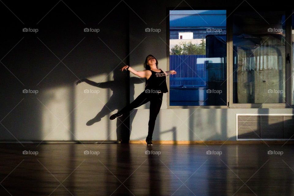 A low arabesque pose in the dance school during the golden hour.