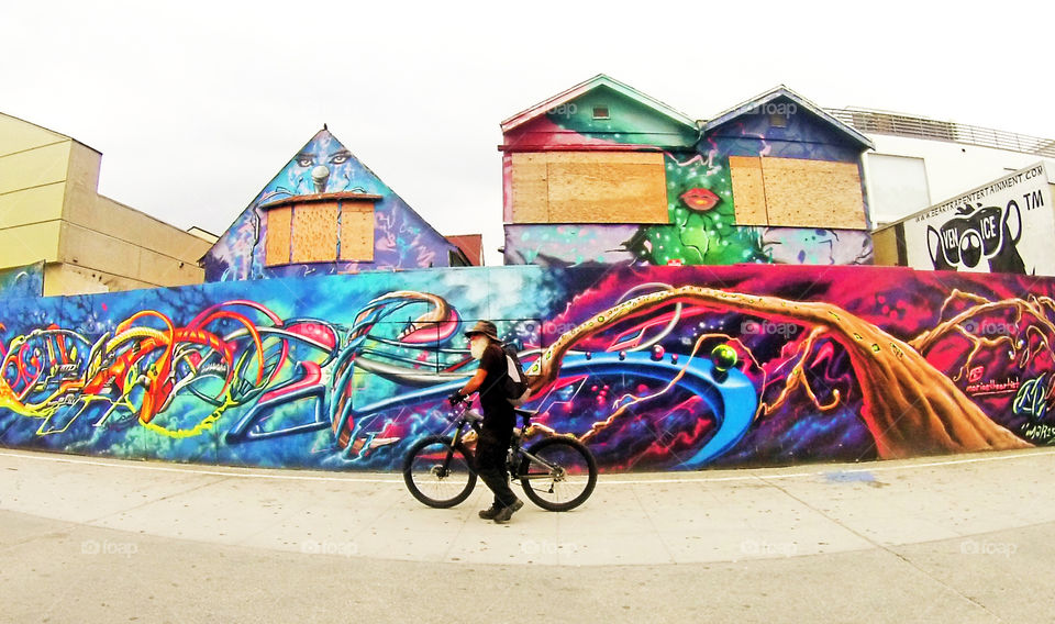 Venice beach wall art mural and a biker passing by