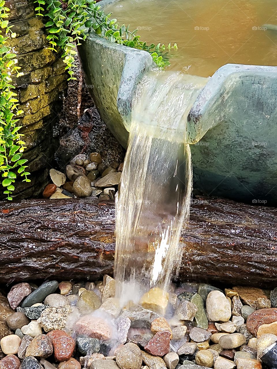 small waterfall with logs and stones