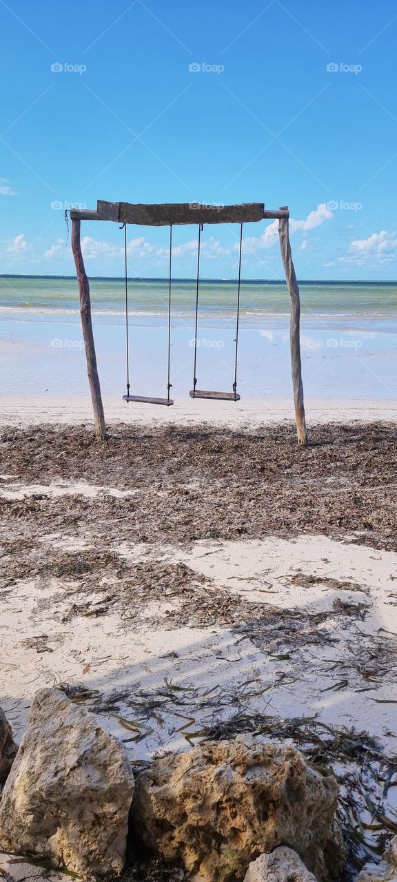paisaje de playa paradisiaco con columpios de madera vacíos en un fondo de mar en calma