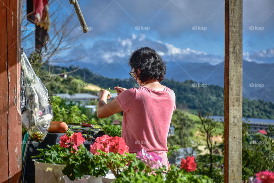 Away from the hustle and bustle of the city life, a lady in a quiet rural area busy with the daily chores.