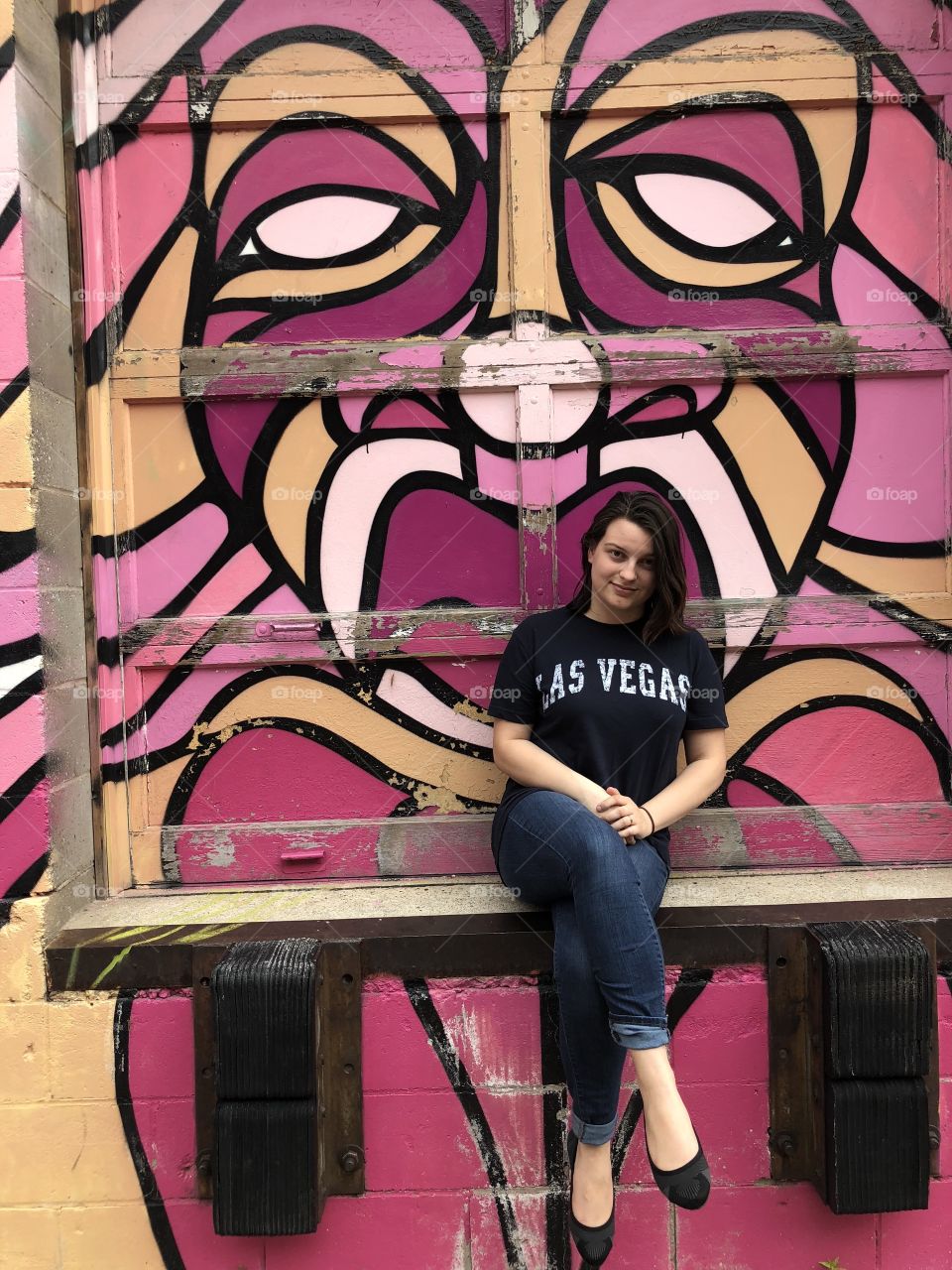 Young Las Vegas woman sitting in front of graffiti.