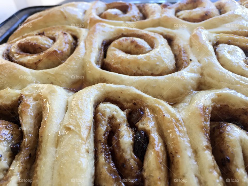 Closeup view home made cinnamon rolls scrolls topped with maple syrup glaze