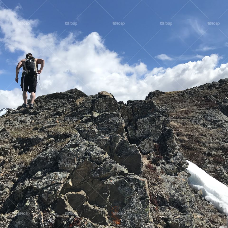 Brave hiker ascending jagged edges of mountain.