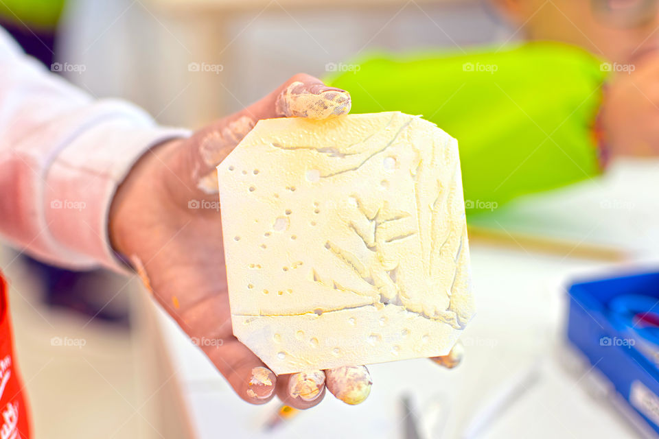 Child holding piece of mold for engraving art at home