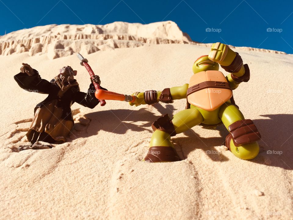 Michelangelo and Shredder fight in the desert sands