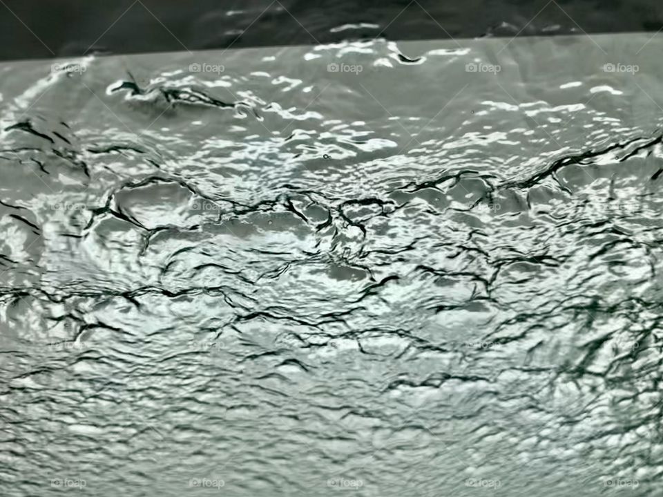 Water splash on car front windshield in a carwash