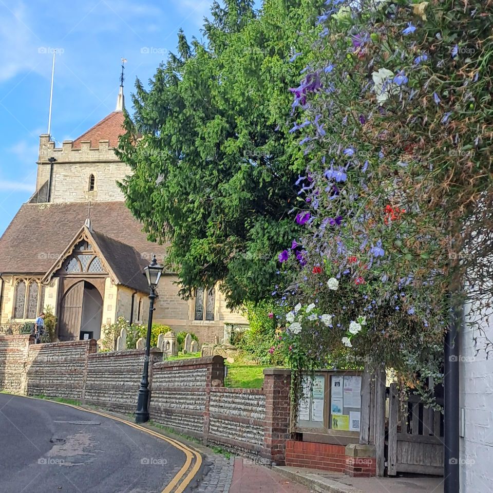 curved road street leading to church with floral arrangements blue sky